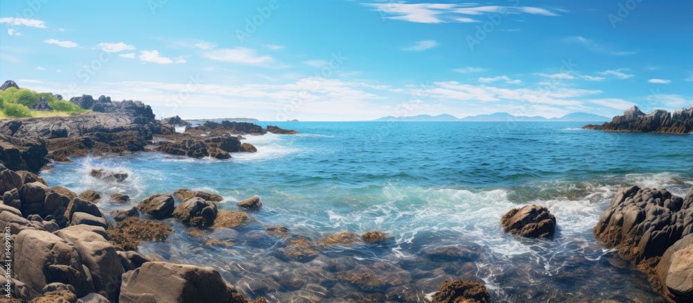 Rocky coast with waves smashing against the rocks on a shoaling beach, under a clear blue sky. with copy space image. Place for adding text or design