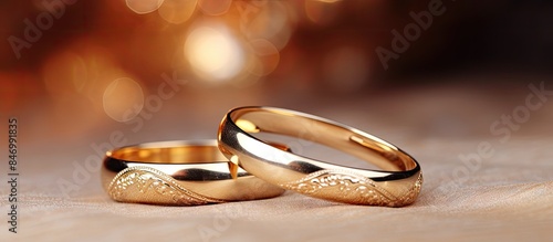 Pair of elegant gold wedding rings resting on a surface, blurred background. Traditional engagement bands with space for copy.