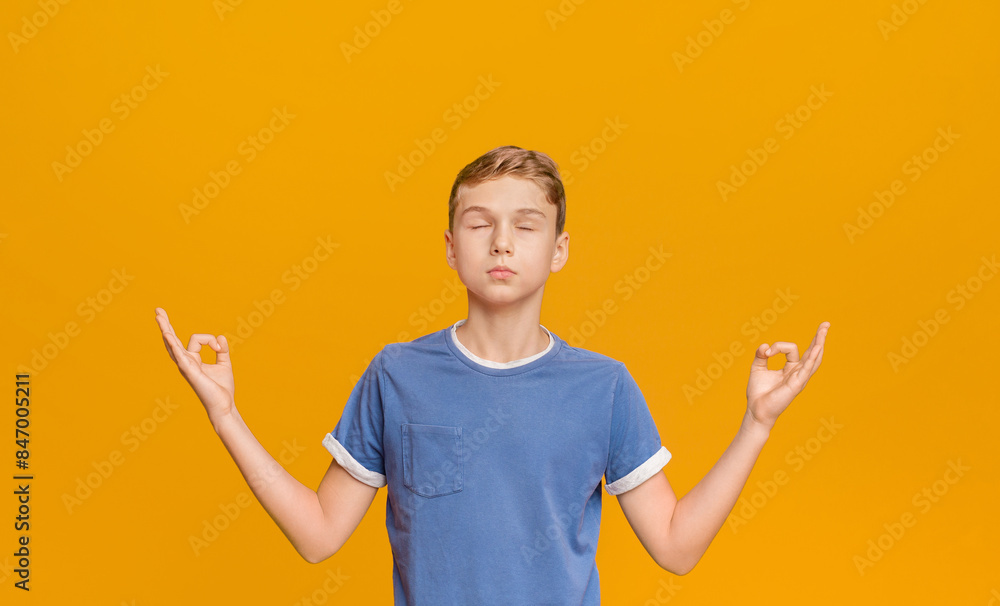 Zen, meditation, balance and peace concept. Portrait of cute little boy holding his fingers in mudra gesture, meditating with closed eyes, orange background Zen, meditation, balance and peace concept. Portrait of cute little boy holding his fingers in mudra gesture, meditating with closed eyes, orange background