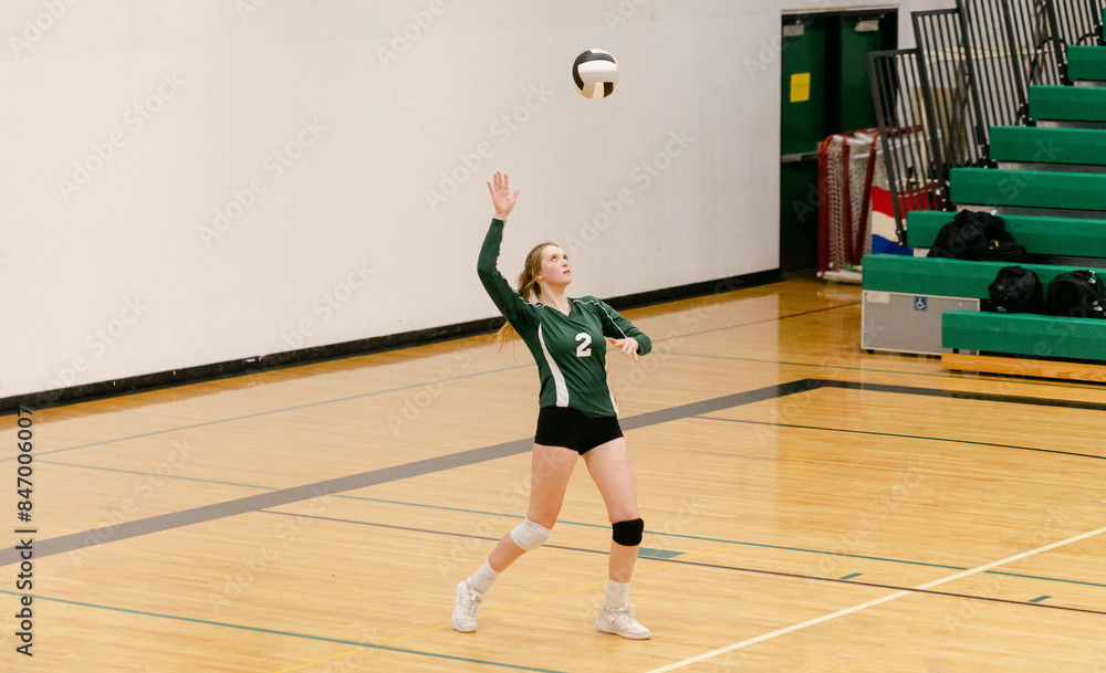 A High School Athlete Serves a Volleyball A High School Athlete Serves a Volleyball
