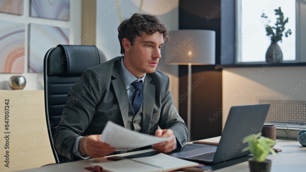Focused boss reading papers working laptop agency closeup. Excited man rejoicing Focused boss reading papers working laptop agency closeup. Excited man rejoicing