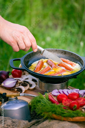 Cooking food in a frying pan, near a fire in the open air.