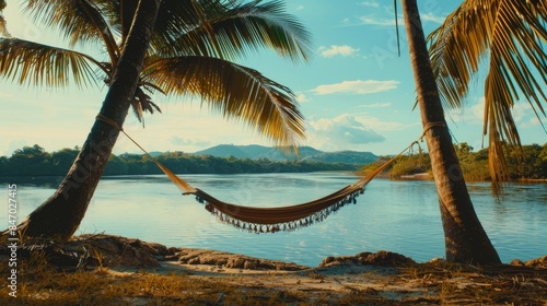 A hammock strung between two palm trees on the beach river's edge, swaying gently in the breeze