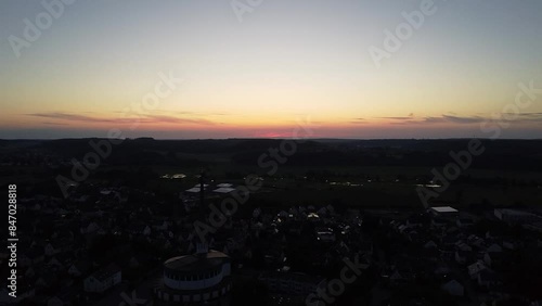 Drohnenaufnahme von hohem Kirchturm von Diedorf bei Sonnenuntergang