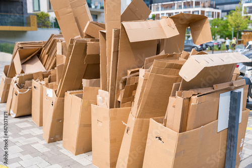 Pile of cardboard boxes ready for recycling outside a building.