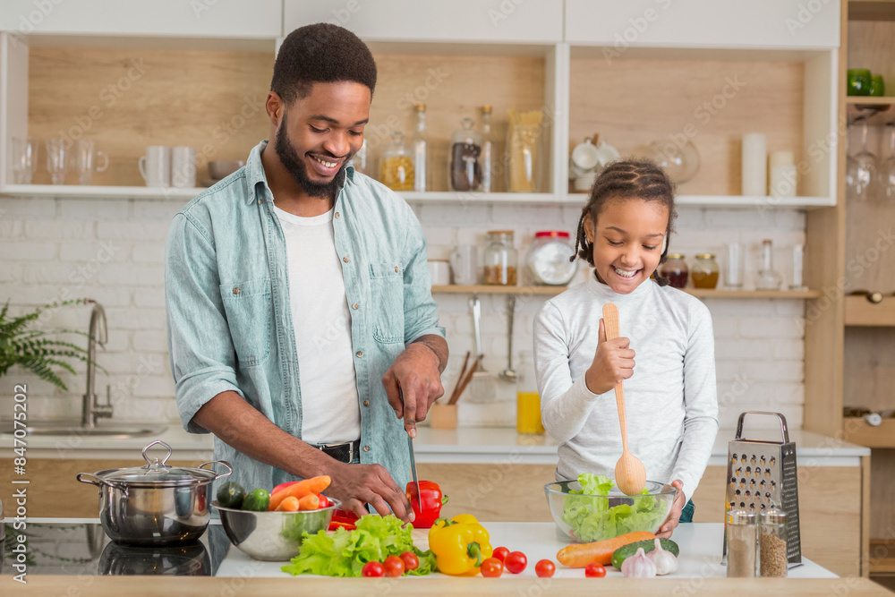 Black father and his daughter give thumbs up while cooking together in the kitchen, enjoying family time and embracing fatherhood Black father and his daughter give thumbs up while cooking together in the kitchen, enjoying family time and embracing fatherhood