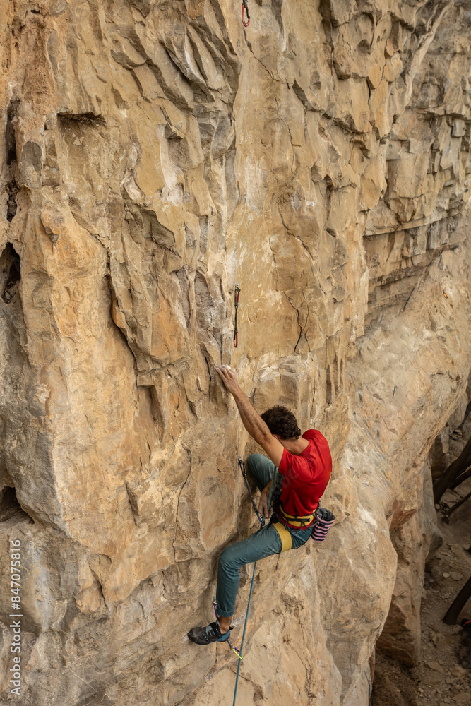 A man is climbing a rock wall in a red shirt. Concept of adventure and excitement as the man navigates the challenging terrain A man is climbing a rock wall in a red shirt. Concept of adventure and excitement as the man navigates the challenging terrain
