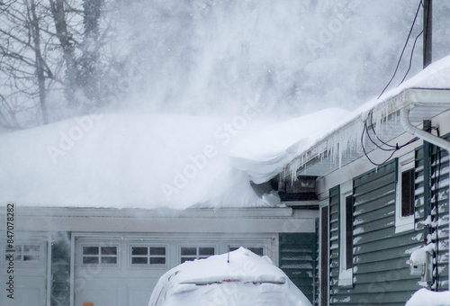 Snow blowing off the roof of a residential house during a blizzard photo