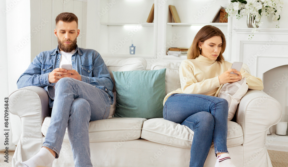 Family quarrel. Couple Staring At Their Own Smartphones, Sitting On Different Sides Of Couch Family quarrel. Couple Staring At Their Own Smartphones, Sitting On Different Sides Of Couch
