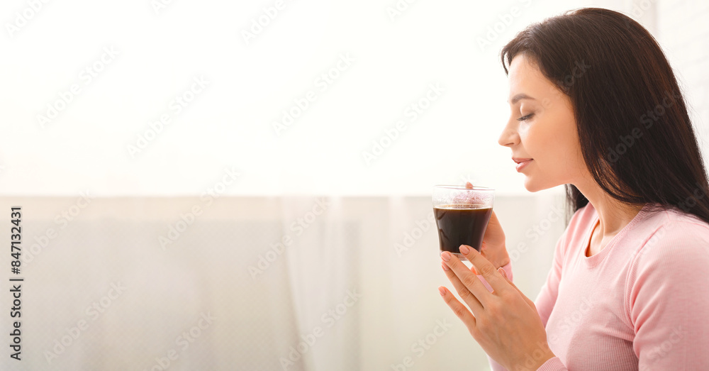 A woman is seen holding a drink in her hand, standing in a casual pose. The focus is on her hand gripping the cup, showcasing a simple and everyday moment, panorama with copy space A woman is seen holding a drink in her hand, standing in a casual pose. The focus is on her hand gripping the cup, showcasing a simple and everyday moment, panorama with copy space
