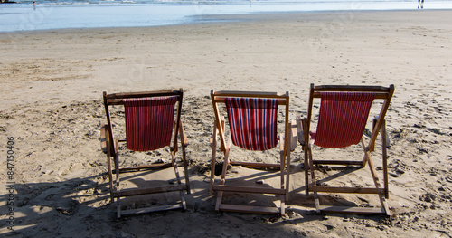 Sillas de descanso en la playa a orilla del mar esperando a los bañistas photo