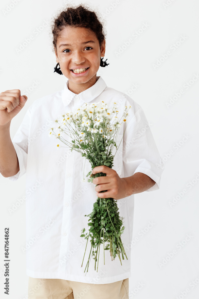 Happy young boy holding a bouquet of daisies in a stylish pose against a clean white backdrop