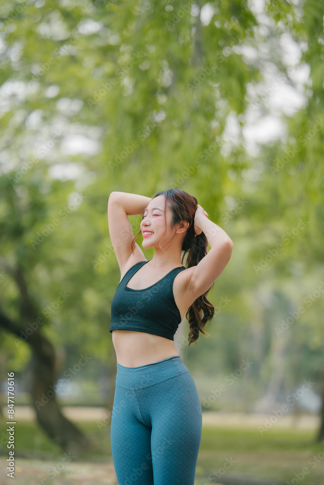 Asian woman trainer is engaged in fitness in public park. Sporty woman does exercises in the open air. Healthy lifestyle, sports outdoor activities in park Asian woman trainer is engaged in fitness in public park. Sporty woman does exercises in the open air. Healthy lifestyle, sports outdoor activities in park
