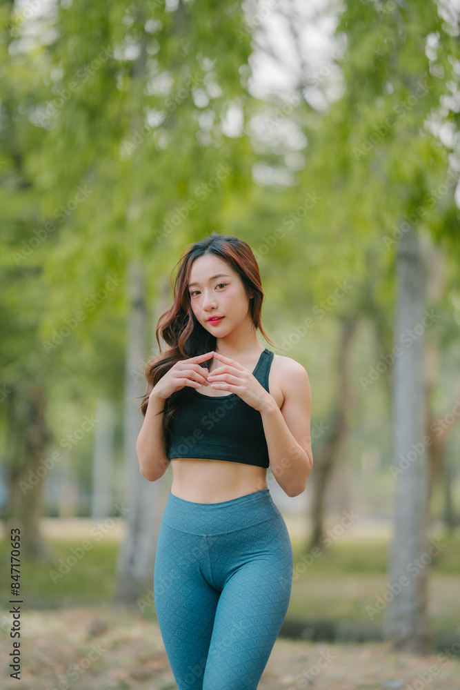 Asian woman trainer is engaged in fitness in public park. Sporty woman does exercises in the open air. Healthy lifestyle, sports outdoor activities in park Asian woman trainer is engaged in fitness in public park. Sporty woman does exercises in the open air. Healthy lifestyle, sports outdoor activities in park