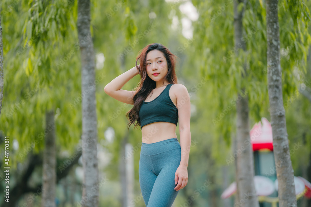 Asian woman trainer is engaged in fitness in public park. Sporty woman does exercises in the open air. Healthy lifestyle, sports outdoor activities in park Asian woman trainer is engaged in fitness in public park. Sporty woman does exercises in the open air. Healthy lifestyle, sports outdoor activities in park
