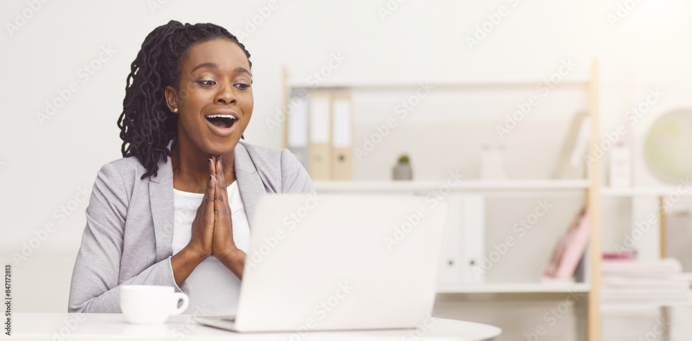 An excited black woman is working on her laptop at the office. The atmosphere is lively and bright, with a modern desk setup, highlighting her enthusiasm and energy. An excited black woman is working on her laptop at the office. The atmosphere is lively and bright, with a modern desk setup, highlighting her enthusiasm and energy.