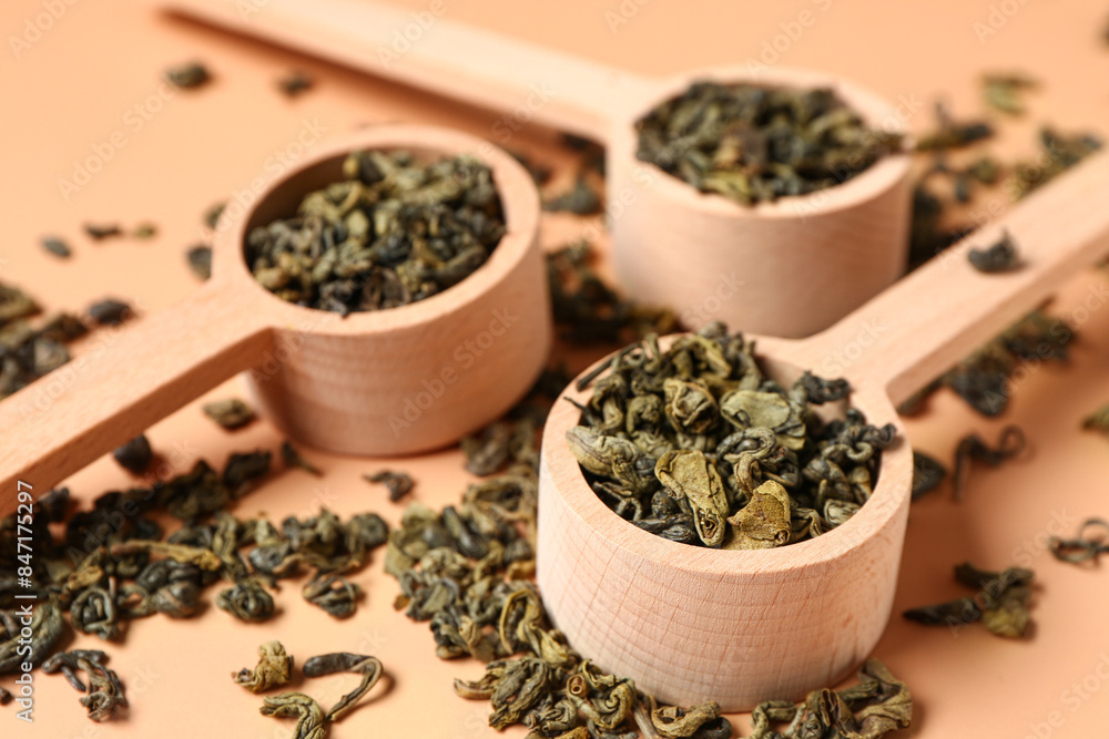 Wooden spoons with dry tea leaves on orange background Wooden spoons with dry tea leaves on orange background