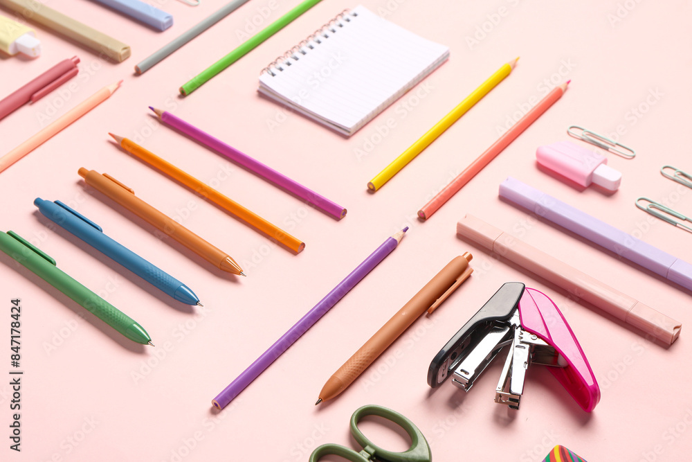 Notebook with different stationery supplies on pink background Notebook with different stationery supplies on pink background