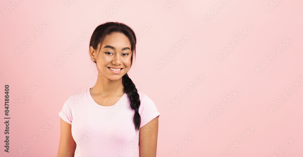 Pretty African American young girl with a pleasant expression on her face is standing in front of a vibrant pink background, smiling confidently, panorama with copy space Pretty African American young girl with a pleasant expression on her face is standing in front of a vibrant pink background, smiling confidently, panorama with copy space