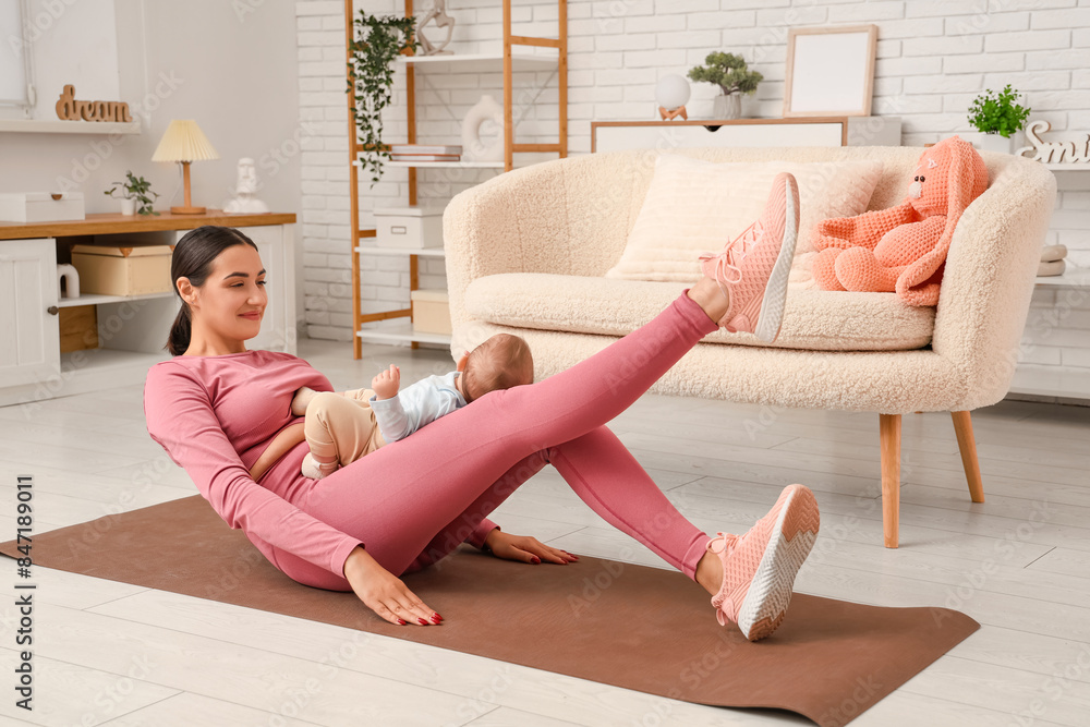 Beautiful young sporty woman with her little baby practicing yoga at home Beautiful young sporty woman with her little baby practicing yoga at home