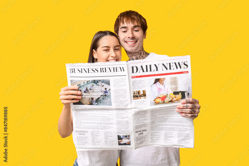 © Pixel-Shot - Young couple with newspaper on yellow background © Pixel-Shot - Young couple with newspaper on yellow background