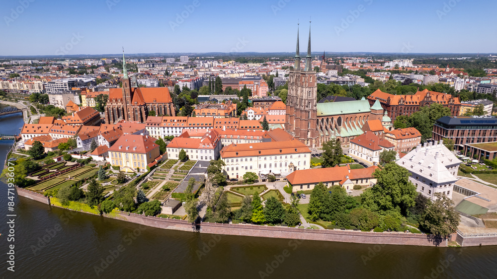 Fototapeta premium A drone view of Ostrów Tumski in Wrocław reveals its historic buildings, charming bridges, and the serene Oder River.
