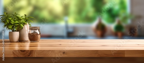 Wooden Tabletop With Plants and Jar in Front of Blurred Kitchen Background © Muhammad