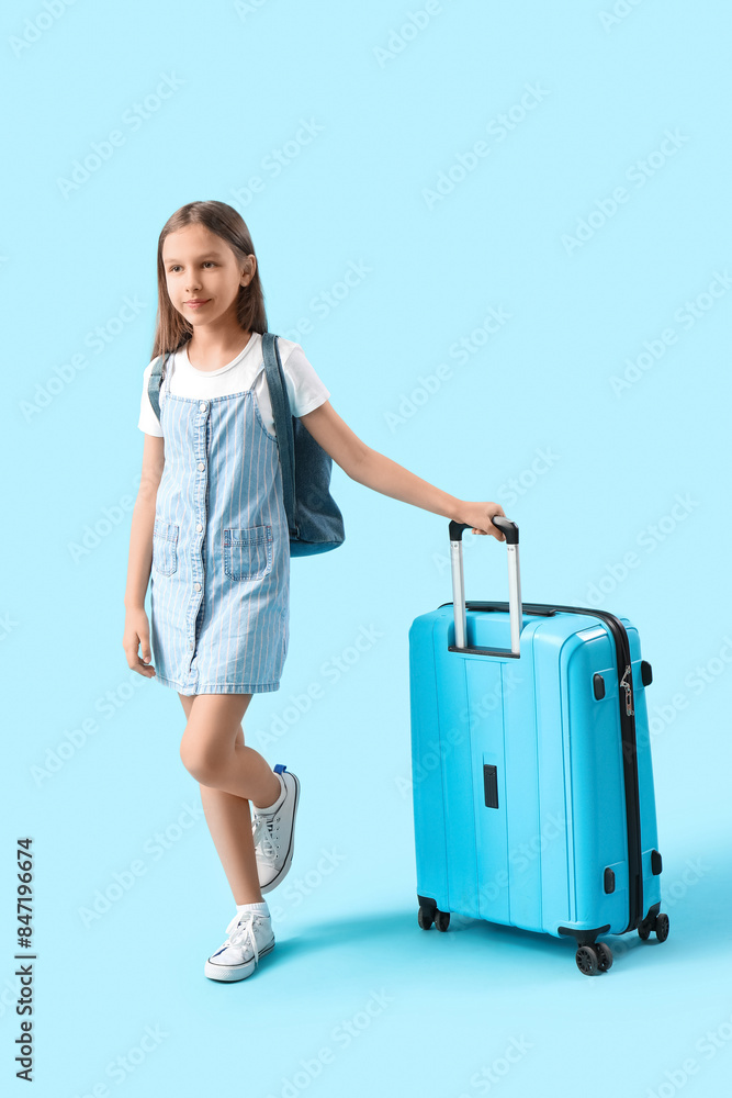 Cute little girl with backpack and suitcase on blue background. Travel concept Cute little girl with backpack and suitcase on blue background. Travel concept