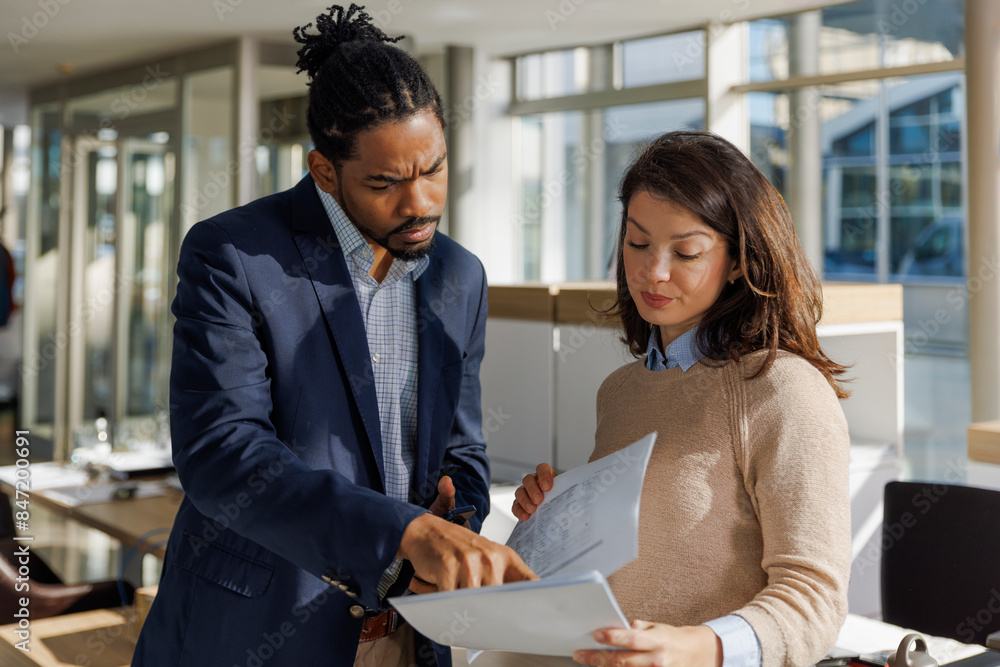 Multiracial entrepreneurs discussing strategy over paper Multiracial entrepreneurs discussing strategy over paper