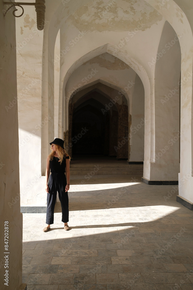 Woman standing in the arched paths of an ancient courtyard Woman standing in the arched paths of an ancient courtyard