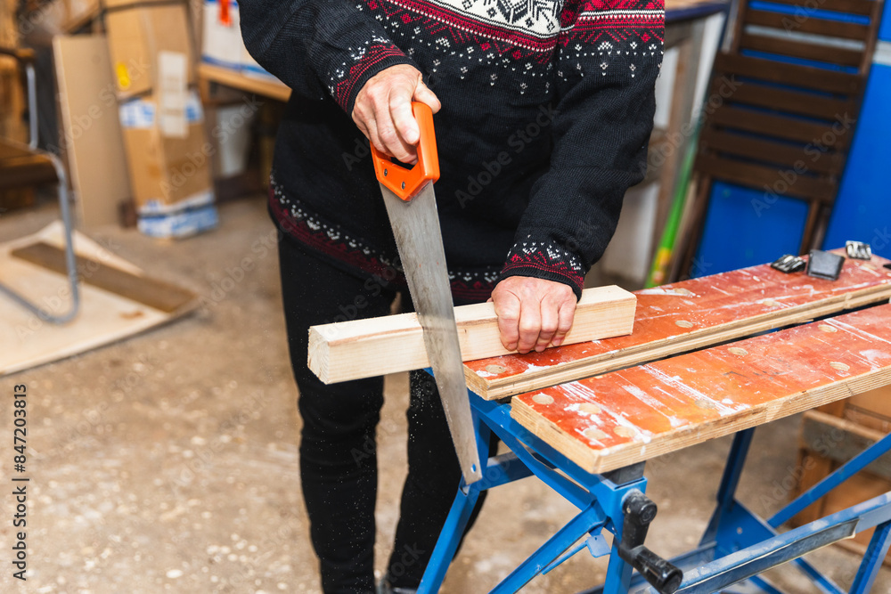 © Diego Martin/Stocksy - Senior woman cutting piece of wood with a saw