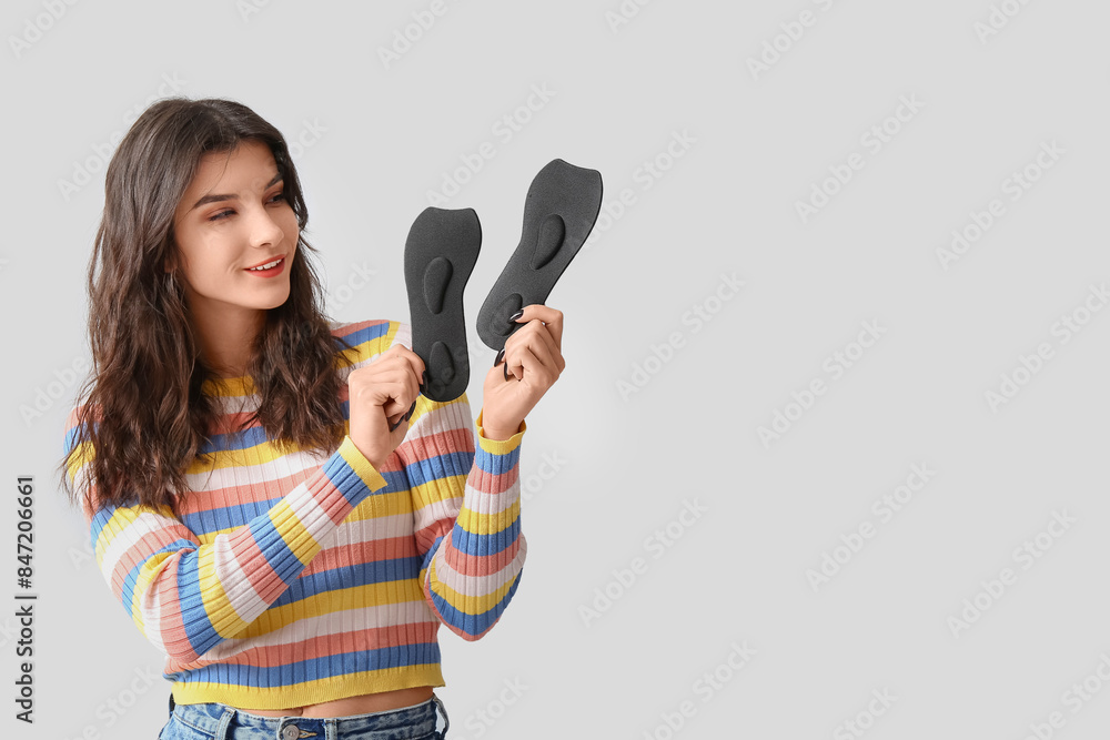 Young woman holding black orthopedic insoles isolated on white background Young woman holding black orthopedic insoles isolated on white background