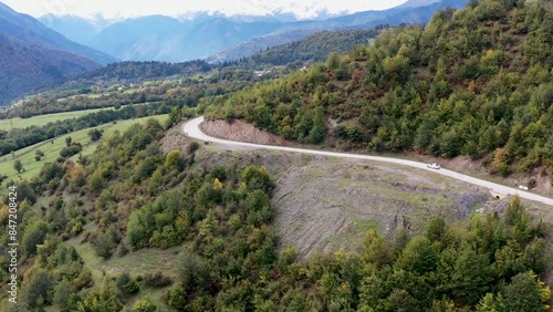Aerial view of the road among the mountains. The car drives among beautiful and high mountains. All around are mountainous expanses, trees, nature. 4k drone video. Sunset over a city skyline.