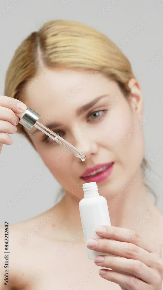 Vertical video. Skin care and rejuvenation. A beautiful blonde woman on a light background uses a skin care cosmetic product. Hydration with serum collagen and hyaluronic acid. Vertical video. Skin care and rejuvenation. A beautiful blonde woman on a light background uses a skin care cosmetic product. Hydration with serum collagen and hyaluronic acid.
