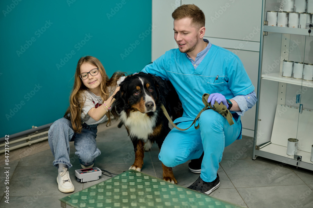 A veterinarian and a little girl weigh her dog A veterinarian and a little girl weigh her dog