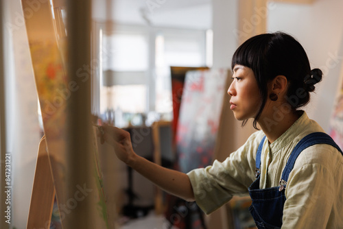 Serious female artist painting in workshop