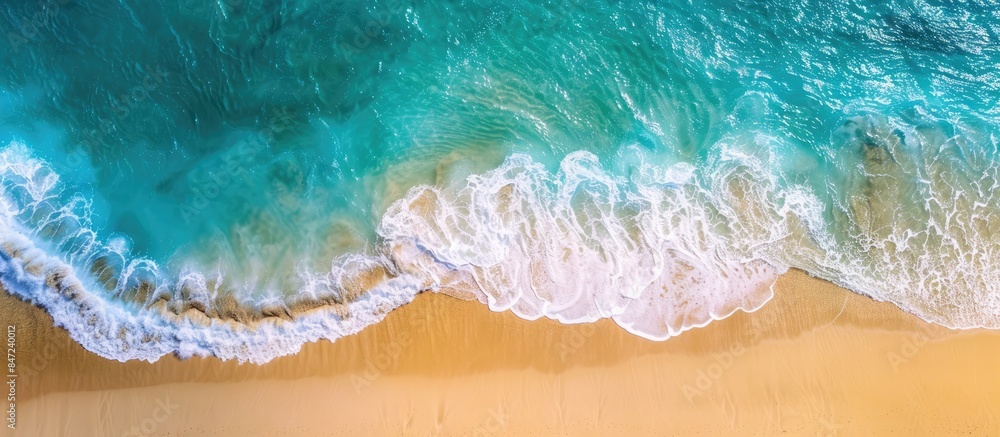 Aerial shot of a pristine beach with golden sand and vibrant blue waters, featuring ample copy space. Aerial shot of a pristine beach with golden sand and vibrant blue waters, featuring ample copy space.