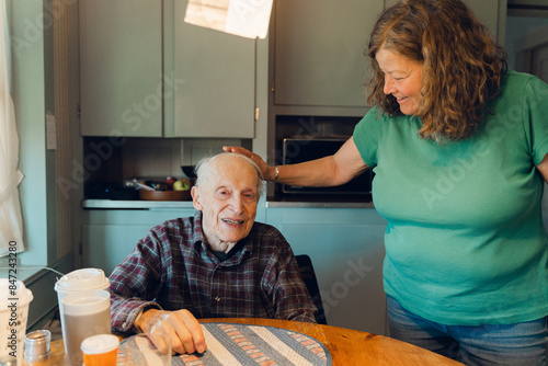 portrait of smiling elderly man  with his daughter in his kitchen   photo