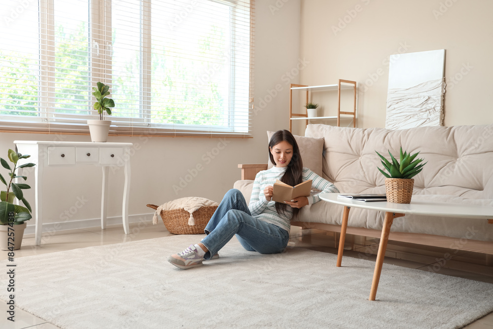 Beautiful young woman reading book and sitting on floor at home Beautiful young woman reading book and sitting on floor at home