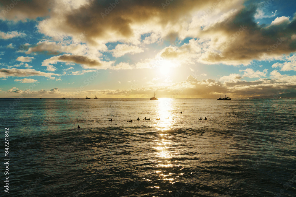 Fototapeta premium Sun sets, casting warm glow over ocean, boats float in distance