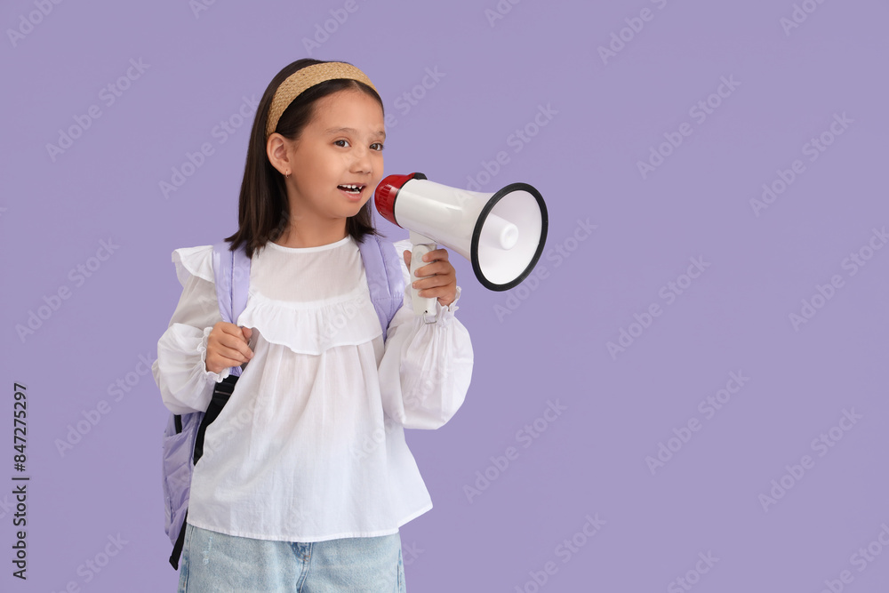 Cute little happy Asian girl with backpack and megaphone on purple background. End of school year Cute little happy Asian girl with backpack and megaphone on purple background. End of school year