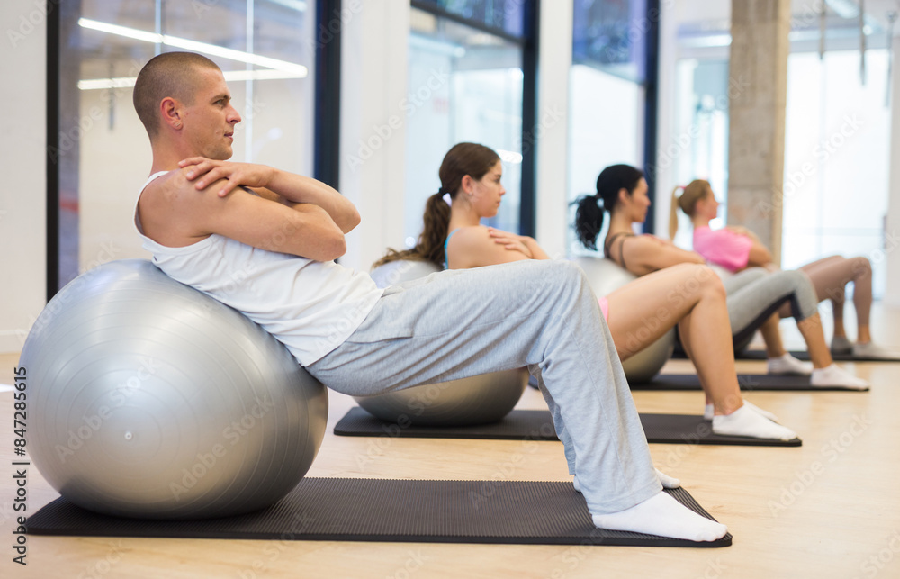 Obraz premium Four people lying on fitness balls and doing crunches