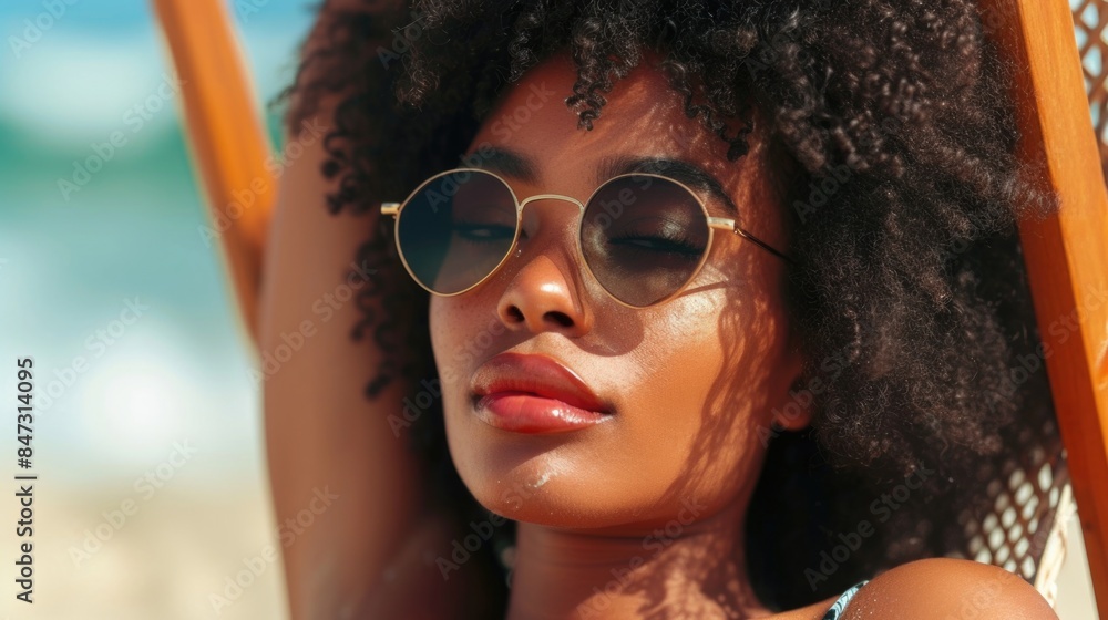 A woman sitting on a beach chair, wearing sunglasses and enjoying the sun A woman sitting on a beach chair, wearing sunglasses and enjoying the sun