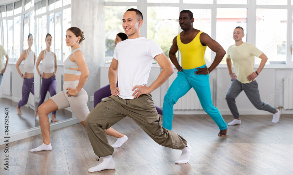 Obraz premium Young happy guy and international dancers preparing their modern dance at light dance studio