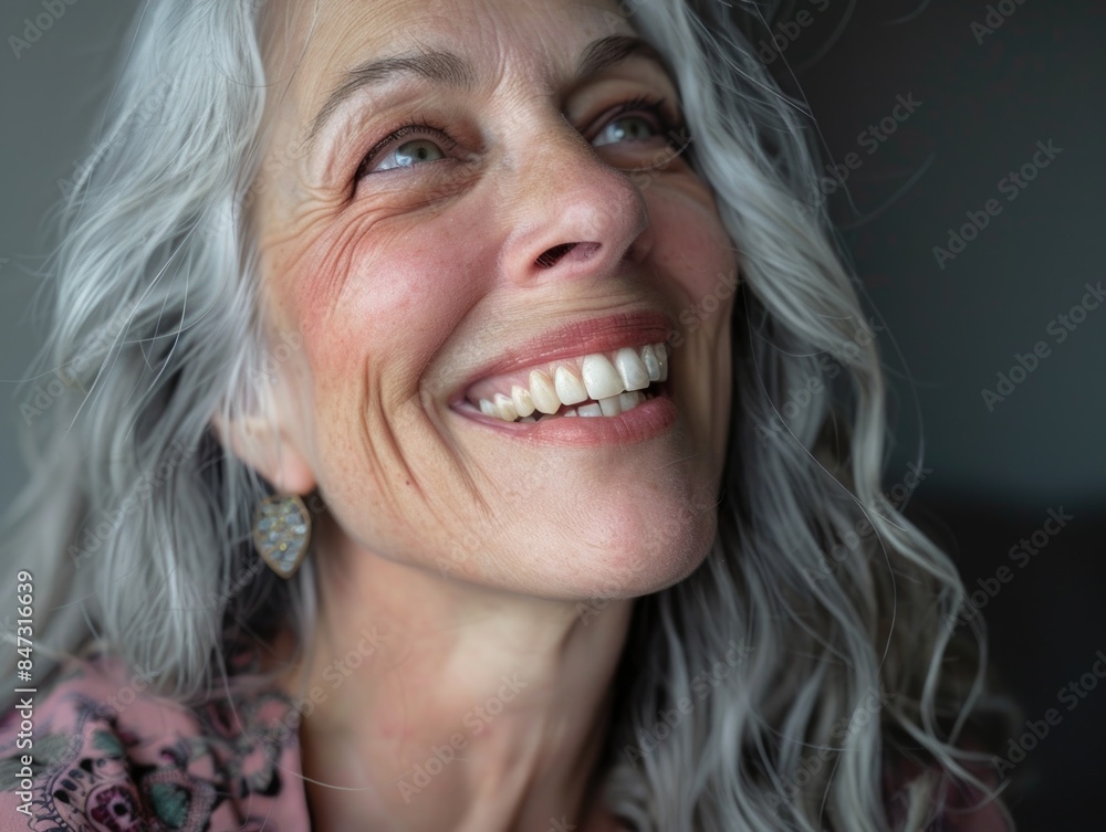 A portrait of an older woman with grey hair and earrings, smiling at the camera A portrait of an older woman with grey hair and earrings, smiling at the camera