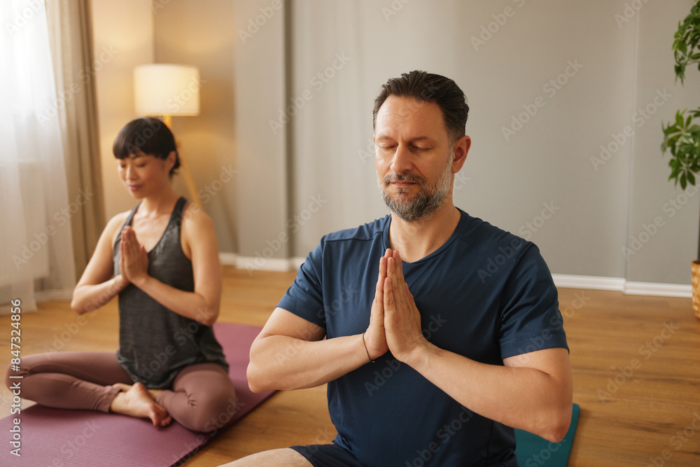 Caucasian man and Asian woman practicing yoga together in yoga studio Caucasian man and Asian woman practicing yoga together in yoga studio