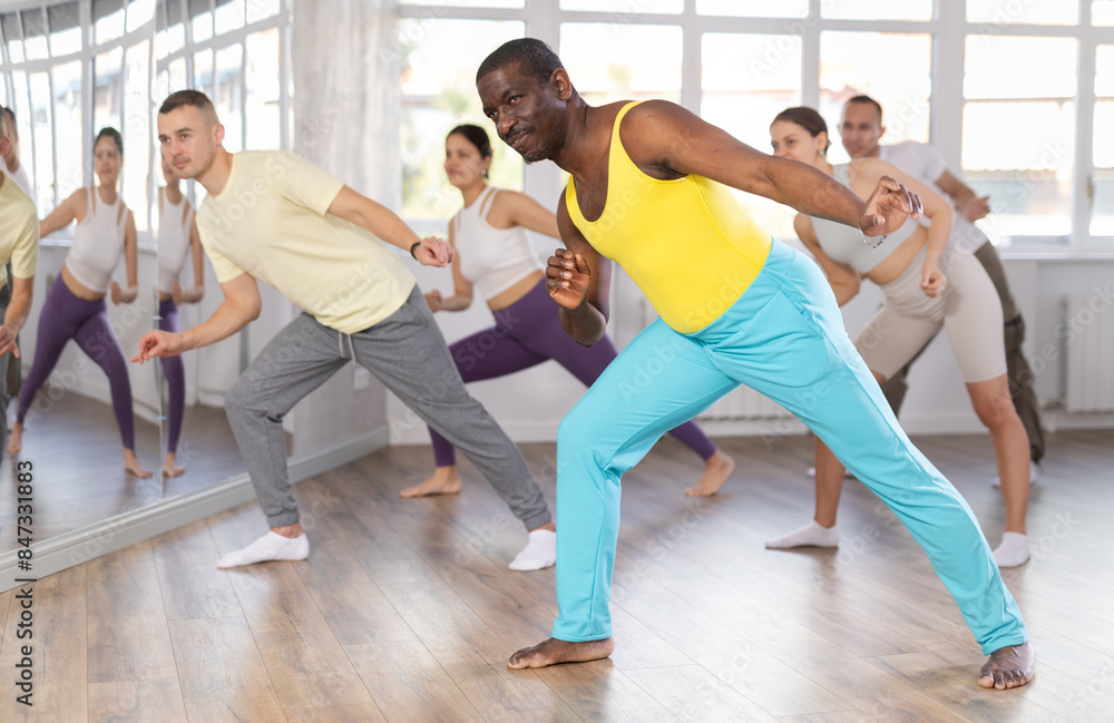 Obraz premium Happy African american man and group of international dancers training modern dance in modern dance class
