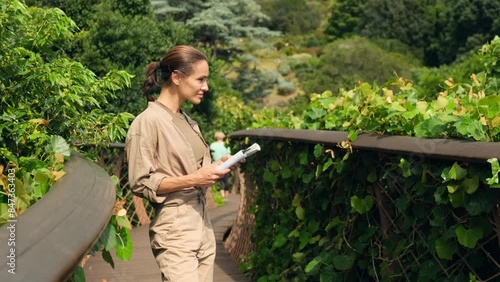 a womale traveler with a backpack and a South African flag holds a map in her hands. woman traveler in hiking overalls holds a paper map in the mountains . tourist traveling along rocky forest trek. photo