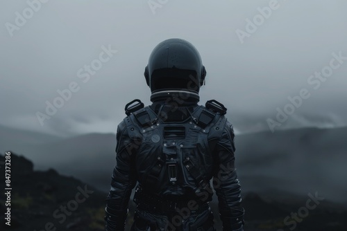 A man in a black spacesuit stands on a mountain