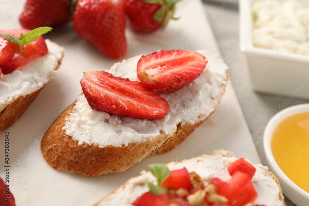 Delicious ricotta bruschettas with strawberry and mint on grey table Delicious ricotta bruschettas with strawberry and mint on grey table